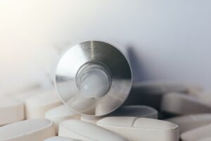 白い長方形の錠剤の上に置かれた銀色のローションポンプのクローズアップ。パッケージングの様子が強調されている。