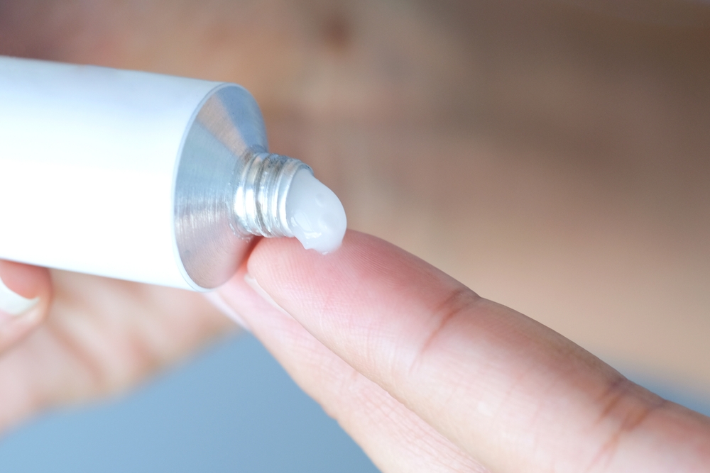 Close-up of white toothpaste being squeezed onto a fingertip from a tube.