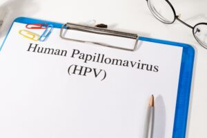 Clipboard featuring a sheet titled 'Human Papillomavirus (HPV)' with colorful paper clips, a pencil, and glasses nearby