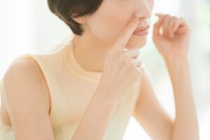 Close-up of a woman gently pinching the skin on her cheek during a skincare routine.
