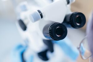 Close-up of a scientific microscope with multiple objective lenses in a laboratory setting.
