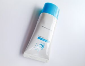 White sunscreen tube with bright blue cap on white surface, SPF 50+ and Extreme UV label.