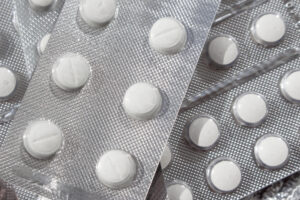 Blister packs with evenly spaced round white pills scattered across a metallic surface.